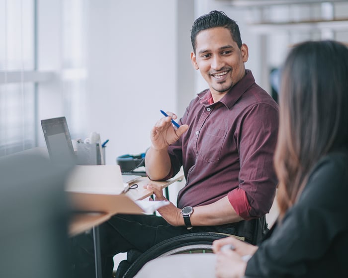 man in wheelchair talking to female coworker