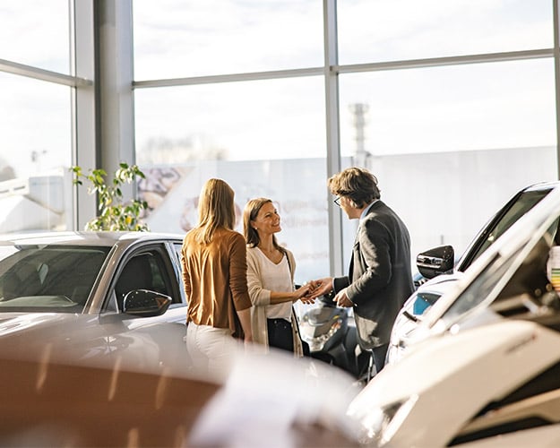 couple talking to car dealership employee