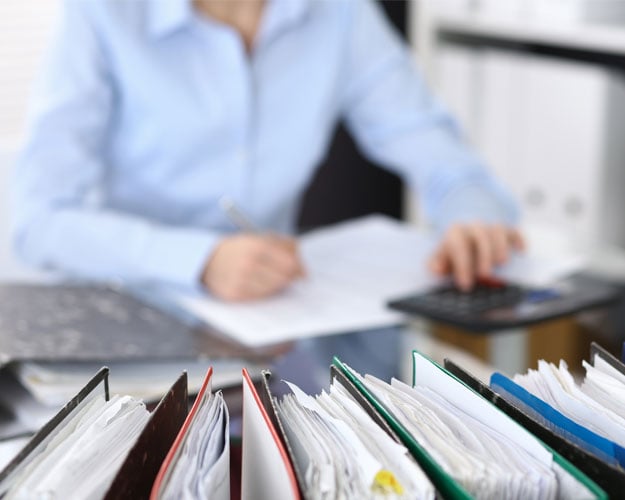 Binders with papers are waiting to be processed with businesswoman