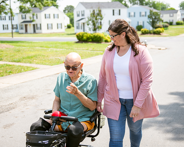 woman and elderly man in wheelchair on a walk