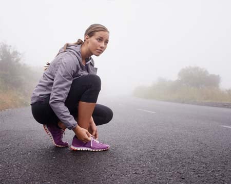 A young female runner tying her shoelace