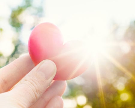 person-holding-heart-shaped-plum-against-the-sun