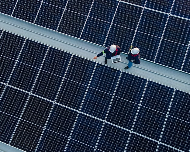 technicians on roof looking at solar panels