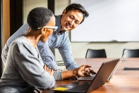 two coworkers looking at laptop