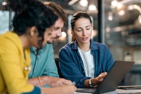 woman showing two coworkers something on a laptop
