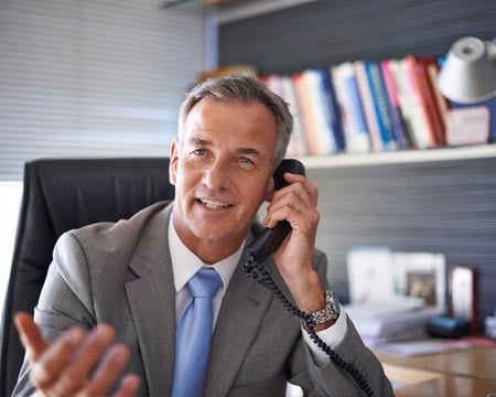 mature businessman looking pleased while talking on the phone