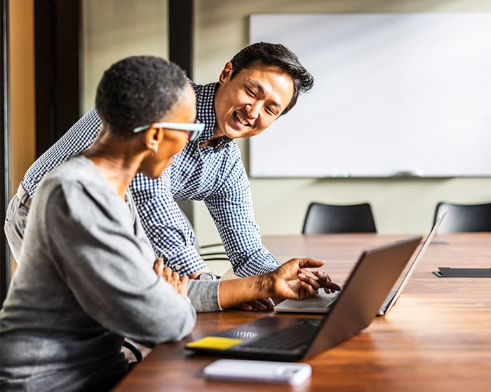 woman asking her male coworker a question on his computer
