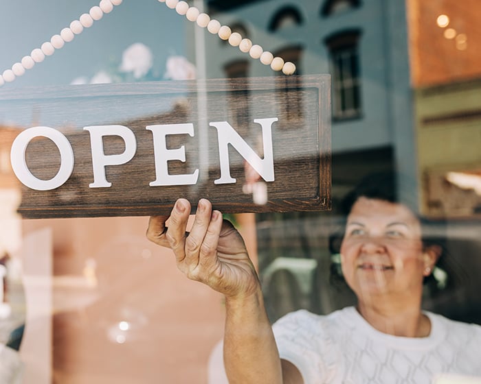 women flipping store sign to open