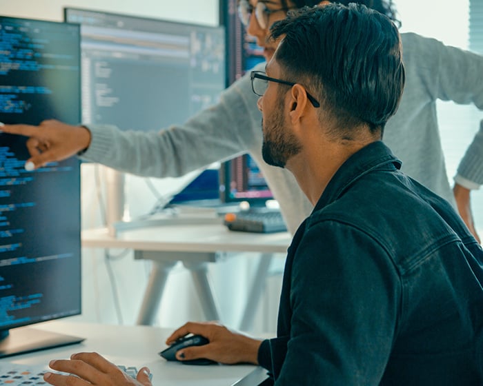 two coworkers looking at code on a computer