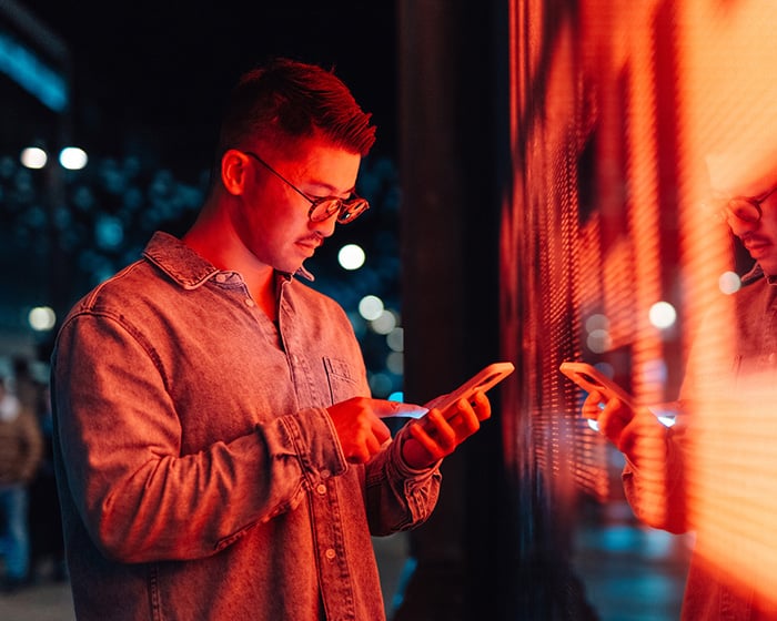 man on phone in front of a neon sign