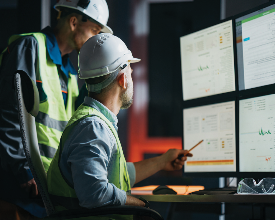 employees in hard hats looking at computer monitors