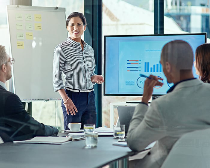 woman presenting data to three coworkers