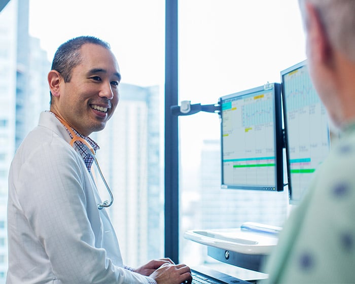 doctor typing on computer while talking to patient