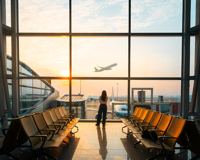 woman looking at a plane through an airport window