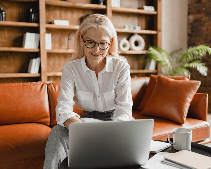 women sitting on couch typing on laptop