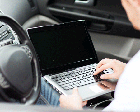 man-typing-on-laptop-computer-in-car