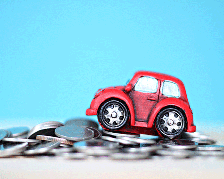 Miniature-car-model-and-coins-on-desk-table