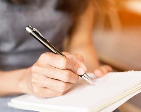 Women holding a pens writing a notebook