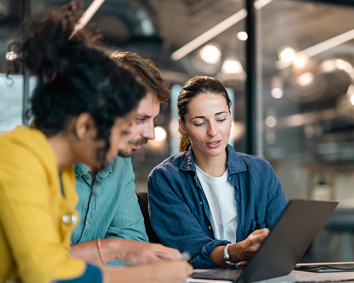 three coworkers looking at a laptop