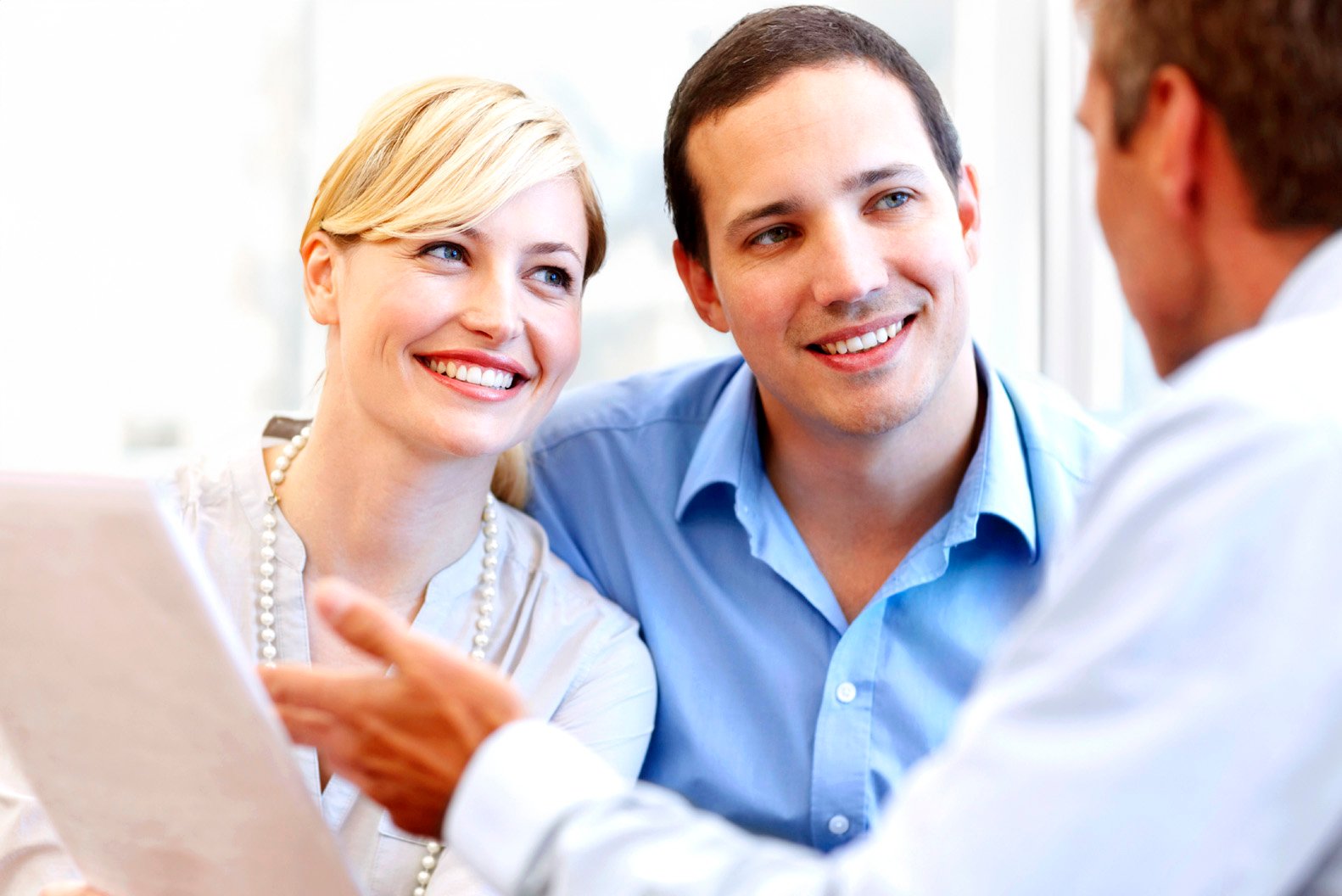 Happy young couple listening intently to their advisor explaining something to them