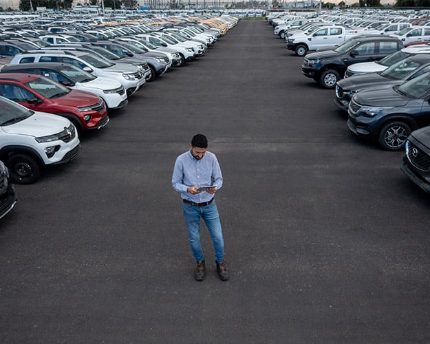 man standing in car dealership lot with tablet