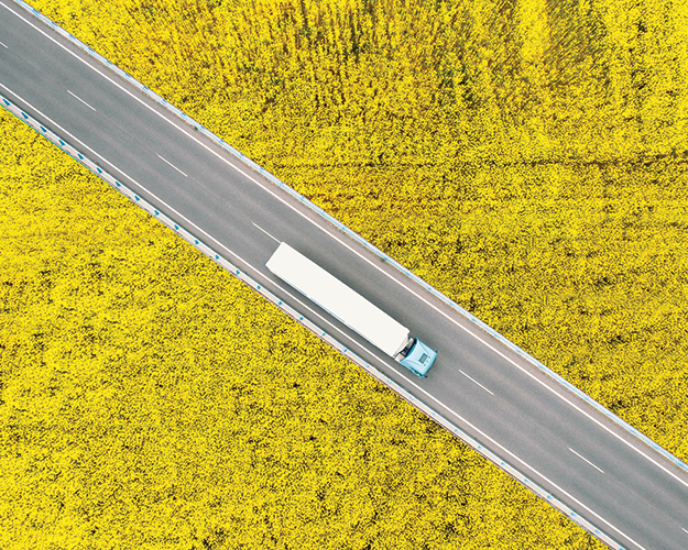 semi driving between canola fields