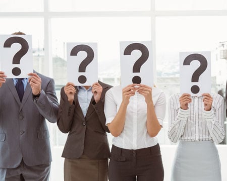 Business-people-holding-question-mark-signs-in-office