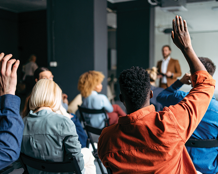 people raising hands in a meeting