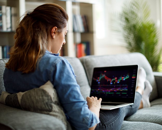 Woman reviewing investment stocks while sitting on couch