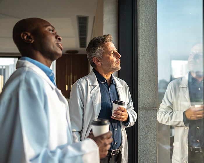 two dentists or doctors looking contemplative out the window
