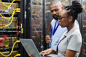 two IT employees looking at equipment