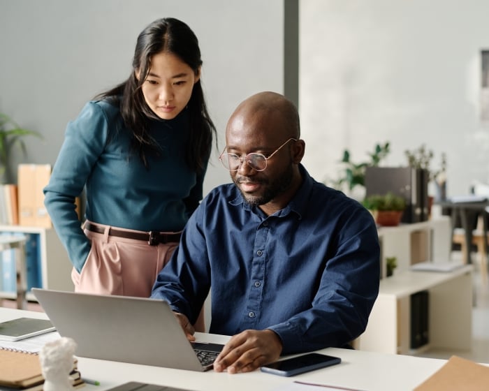 two coworkers looking at a laptop