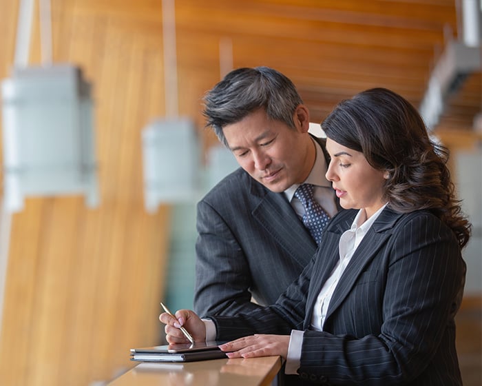 man and woman talking over notebook