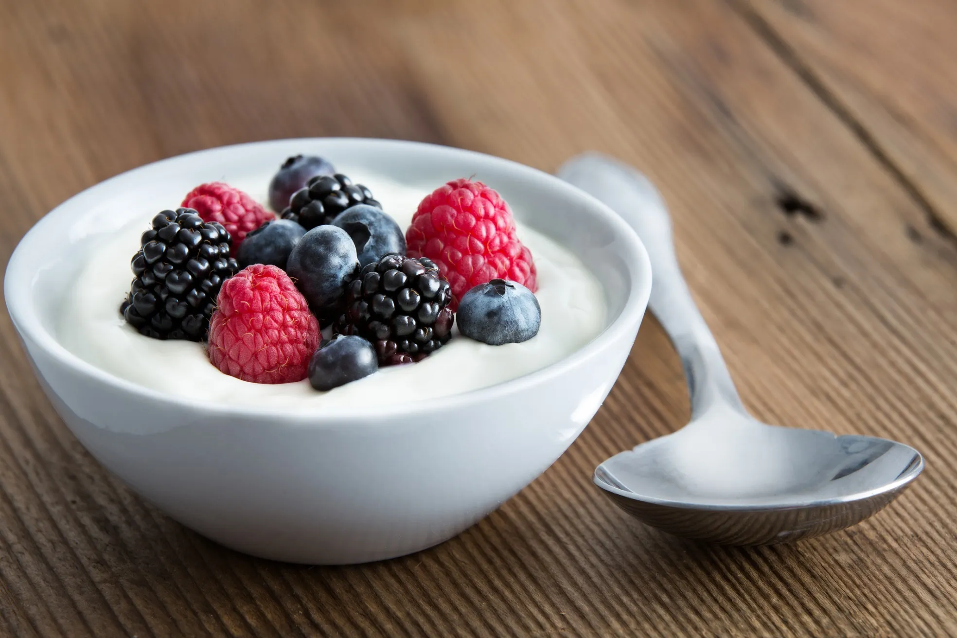 A bowl of yogurt, blueberries and raspberries.