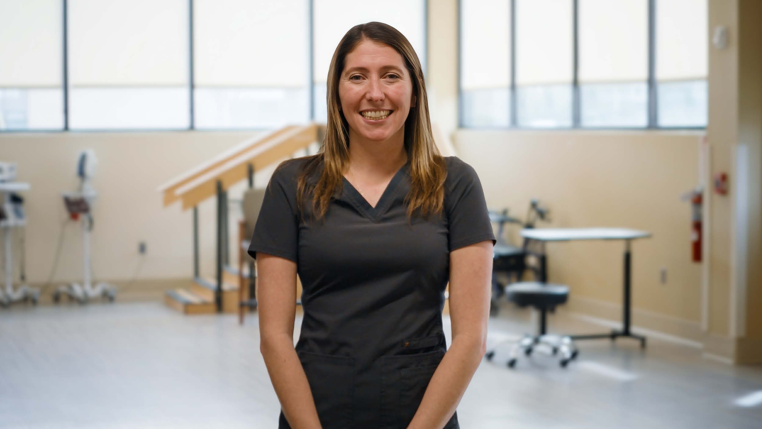 Rehabilitation hospital employee Sara Whitney recognized as OEAA Northeast winner, pictured in dark scrubs within a hospital environment representing clinical leadership and staff achievement.