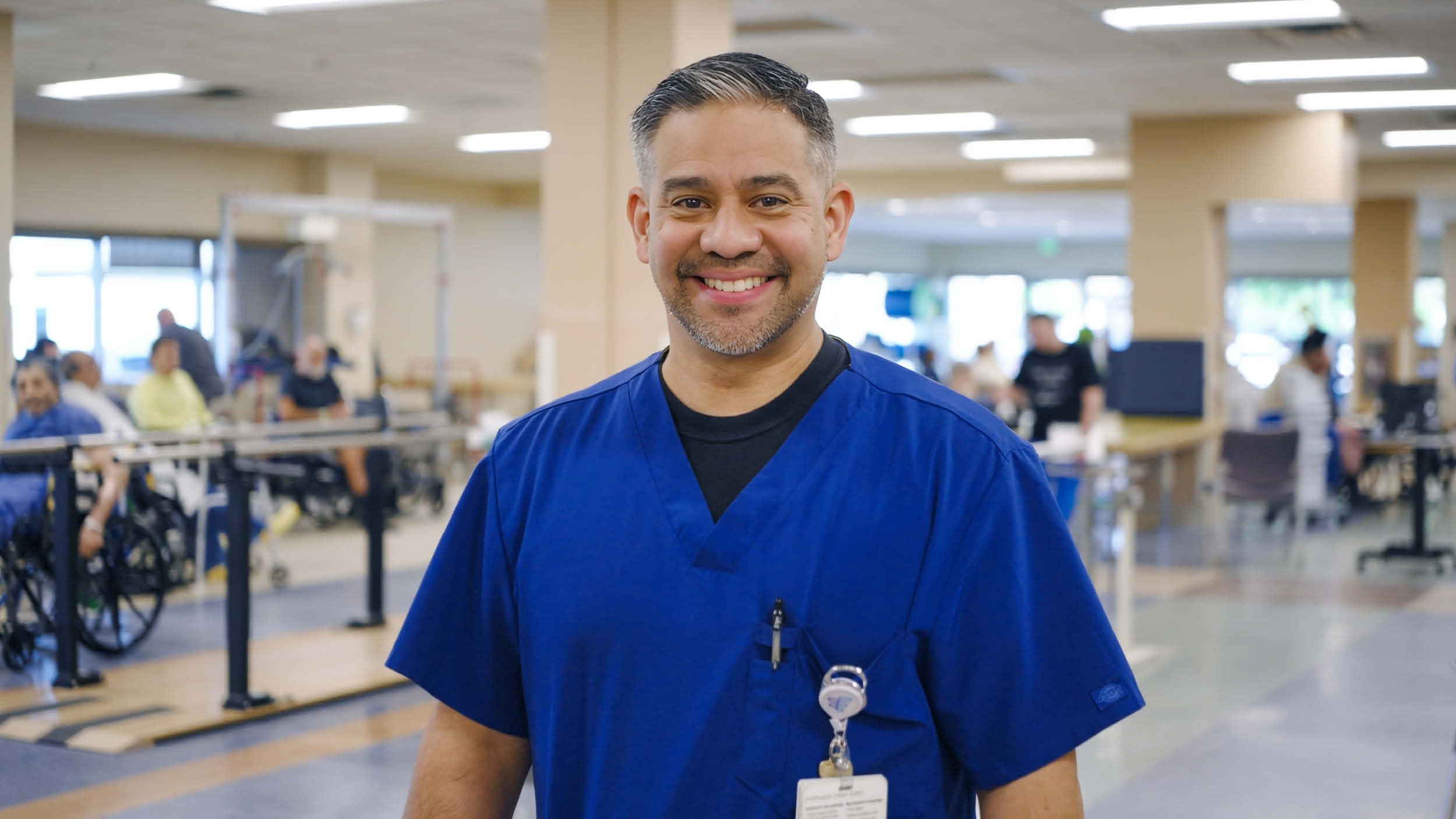 Rehabilitation hospital employee Jerry Garzaro recognized as OEAA West winner, pictured in scrubs within a therapy gym environment representing clinical leadership and staff achievement.