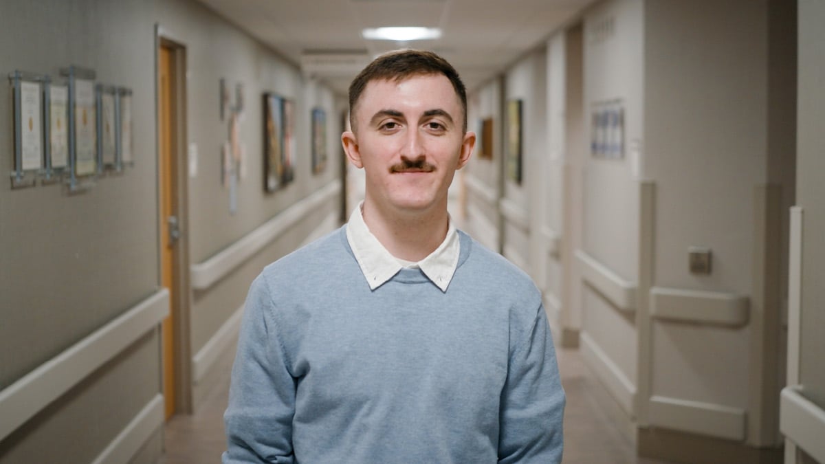 Rehabilitation hospital employee Jacob Smith recognized as OEAA Central winner, pictured in a light blue sweater over a white collared shirt within a hospital hallway, representing clinical leadership and staff achievement.