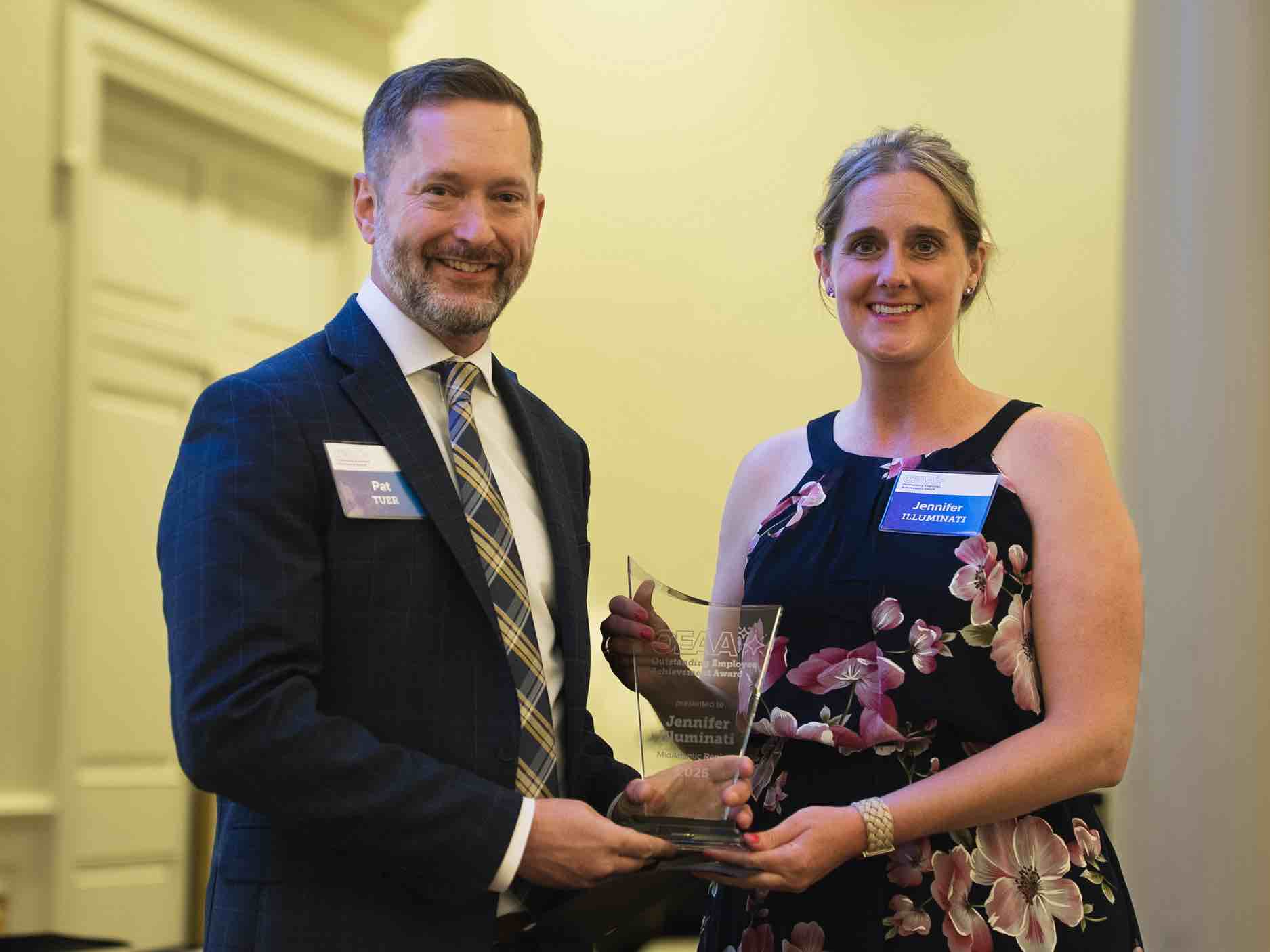 Jennifer Illuminati stands at an OEAA awards presentation, holding a recognition plaque alongside a colleague, representing leadership and excellence in rehabilitation health care achievement and service.