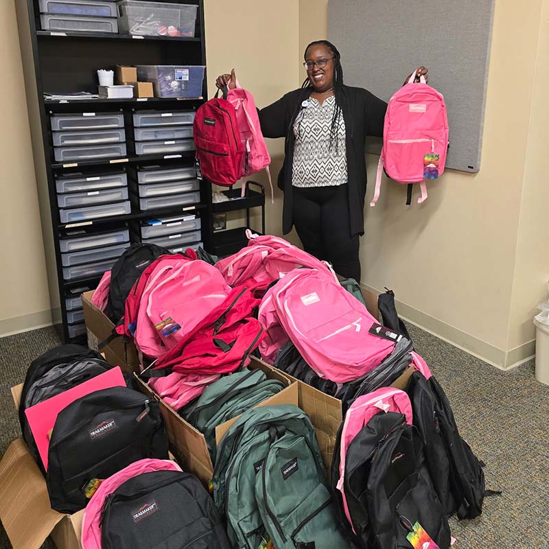 An Encompass Health employee holding up collected backpacks