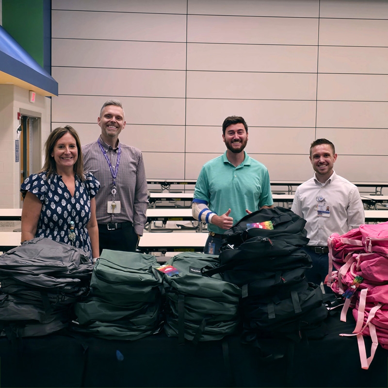 Encompass Health employees behind a pile of collected backpacks