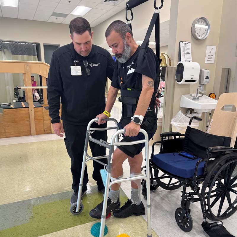 Encompass Health patient taking steps forward while using Aretech ZeroG 3D with an inpatient physical therapist