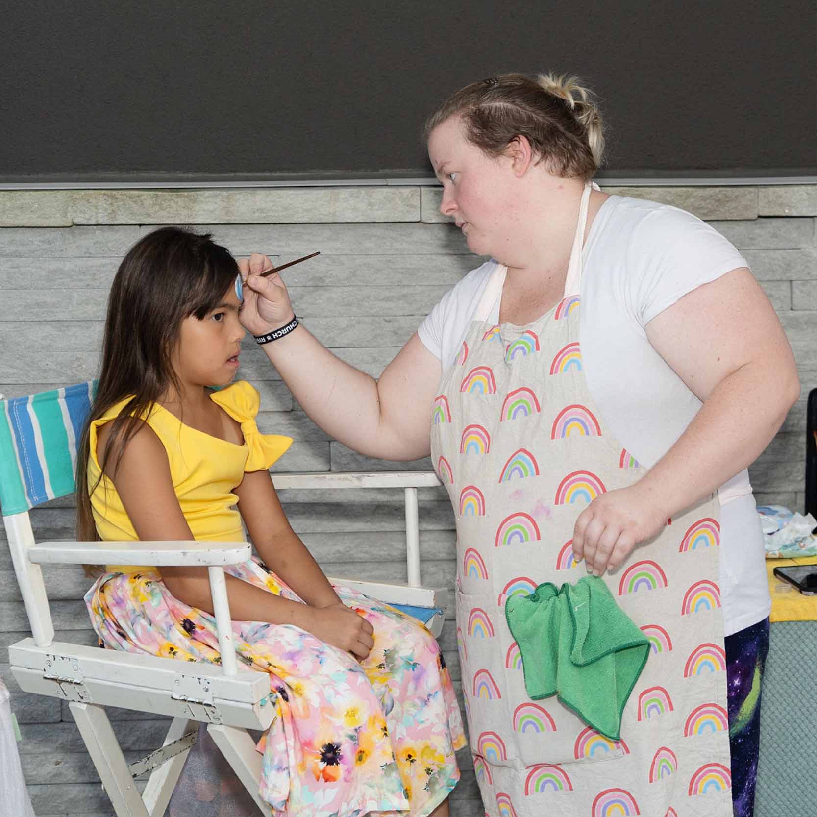An artist doing face paint for a kid