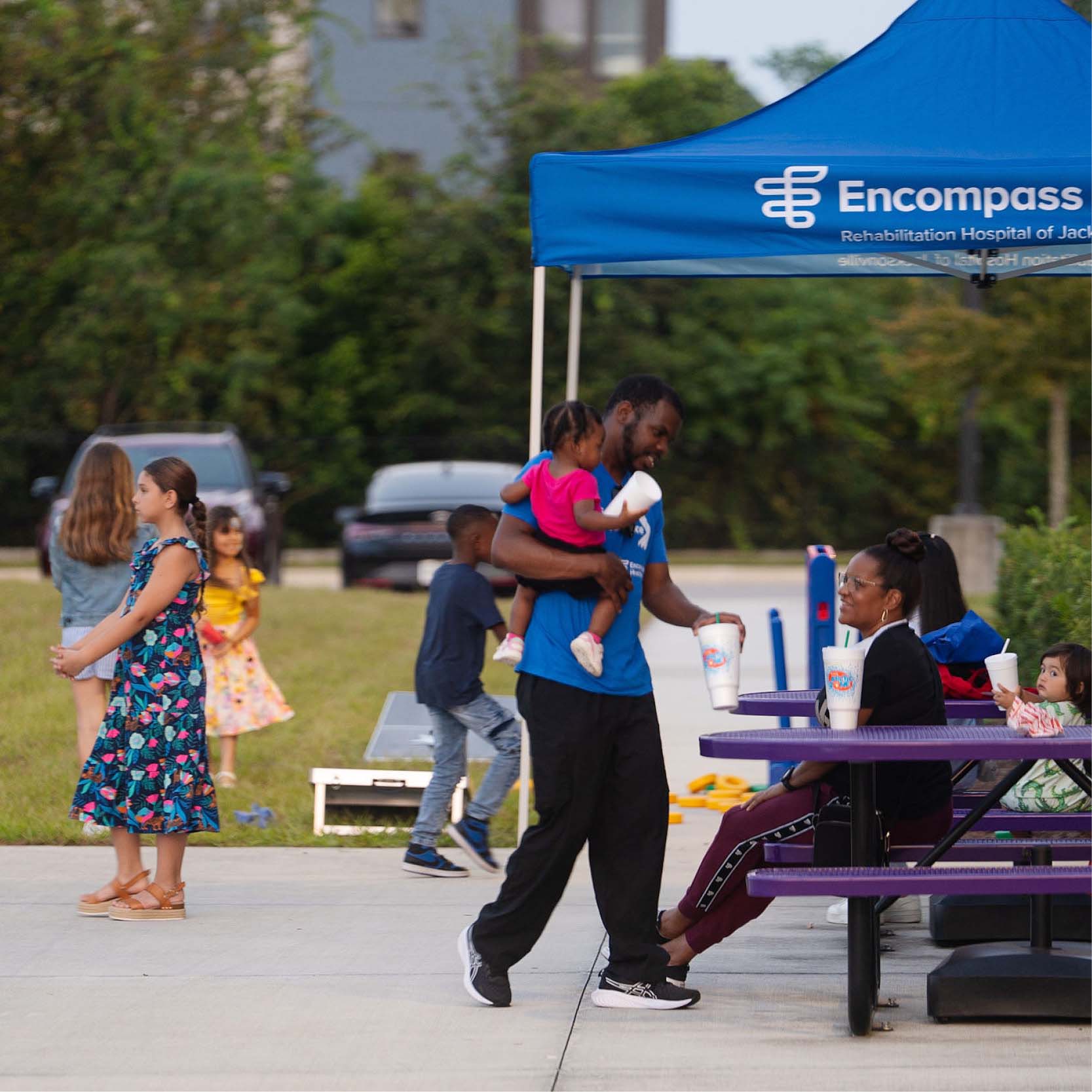 Family celebrating outside under Encompass Health tents