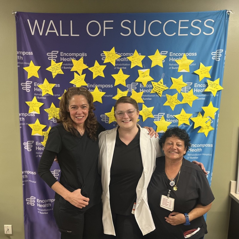 Ashley Brewer with Kenia Lewis, and Susan Sehat stand in front of a 