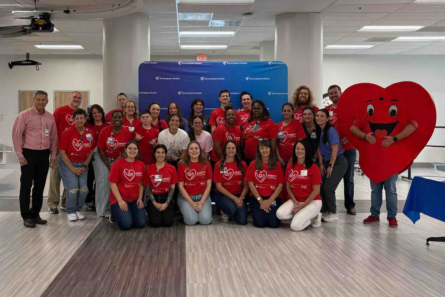 Stroke Field Day team photo of rehabilitation hospital staff wearing red shirts beside a large heart mascot, highlighting coordinated stroke care, therapy services, and patient support programs
