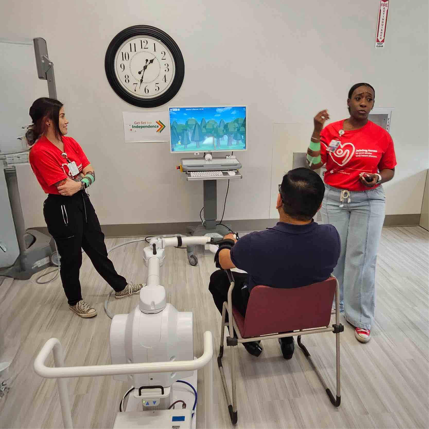 Stroke Field Day technology station with clinician instructing participant using interactive rehab cycling equipment, supporting stroke recovery, coordination training, and functional mobility