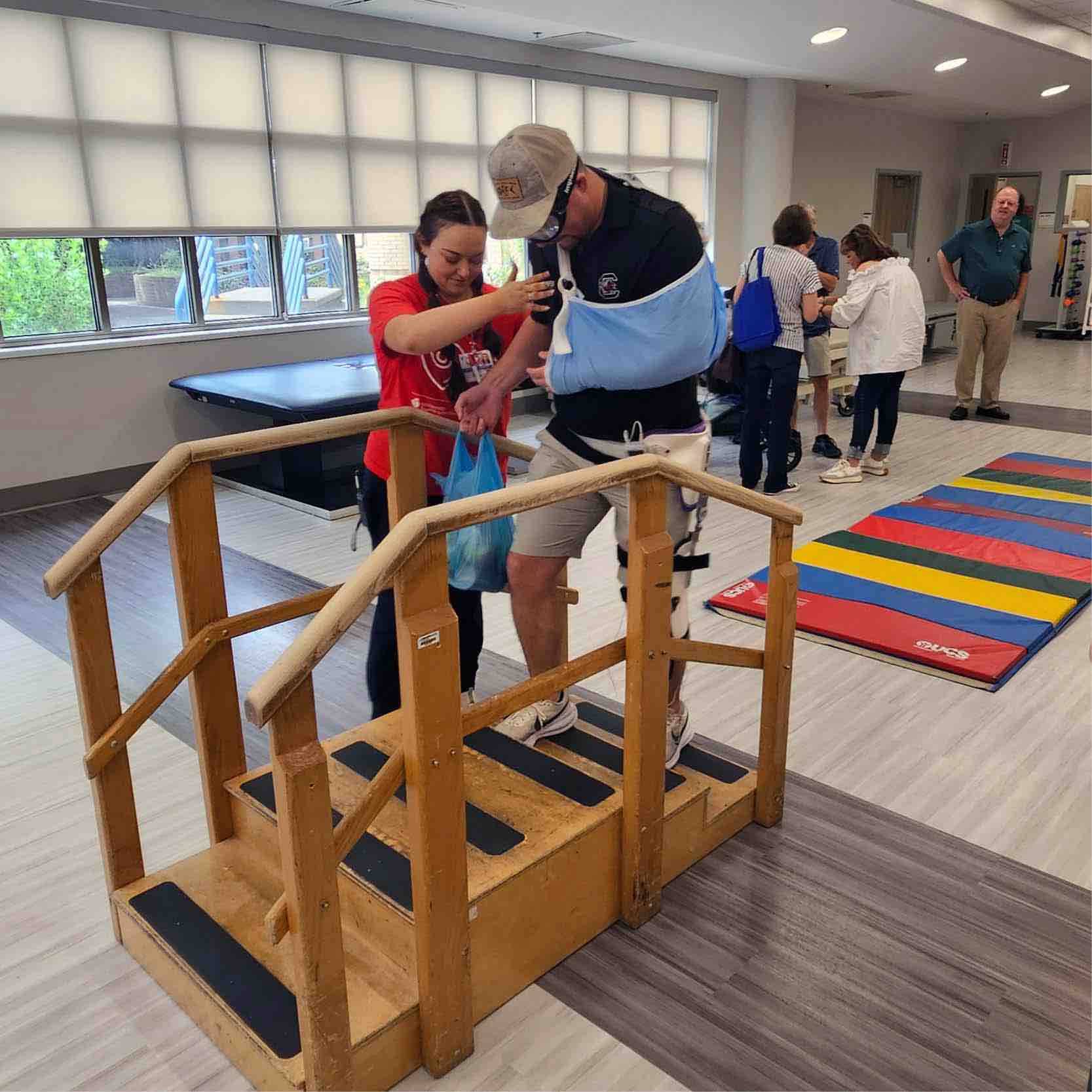 Stroke Field Day therapy station featuring clinician assisting participant on stair training equipment, promoting stroke rehabilitation, balance, strength, and safe mobility skills