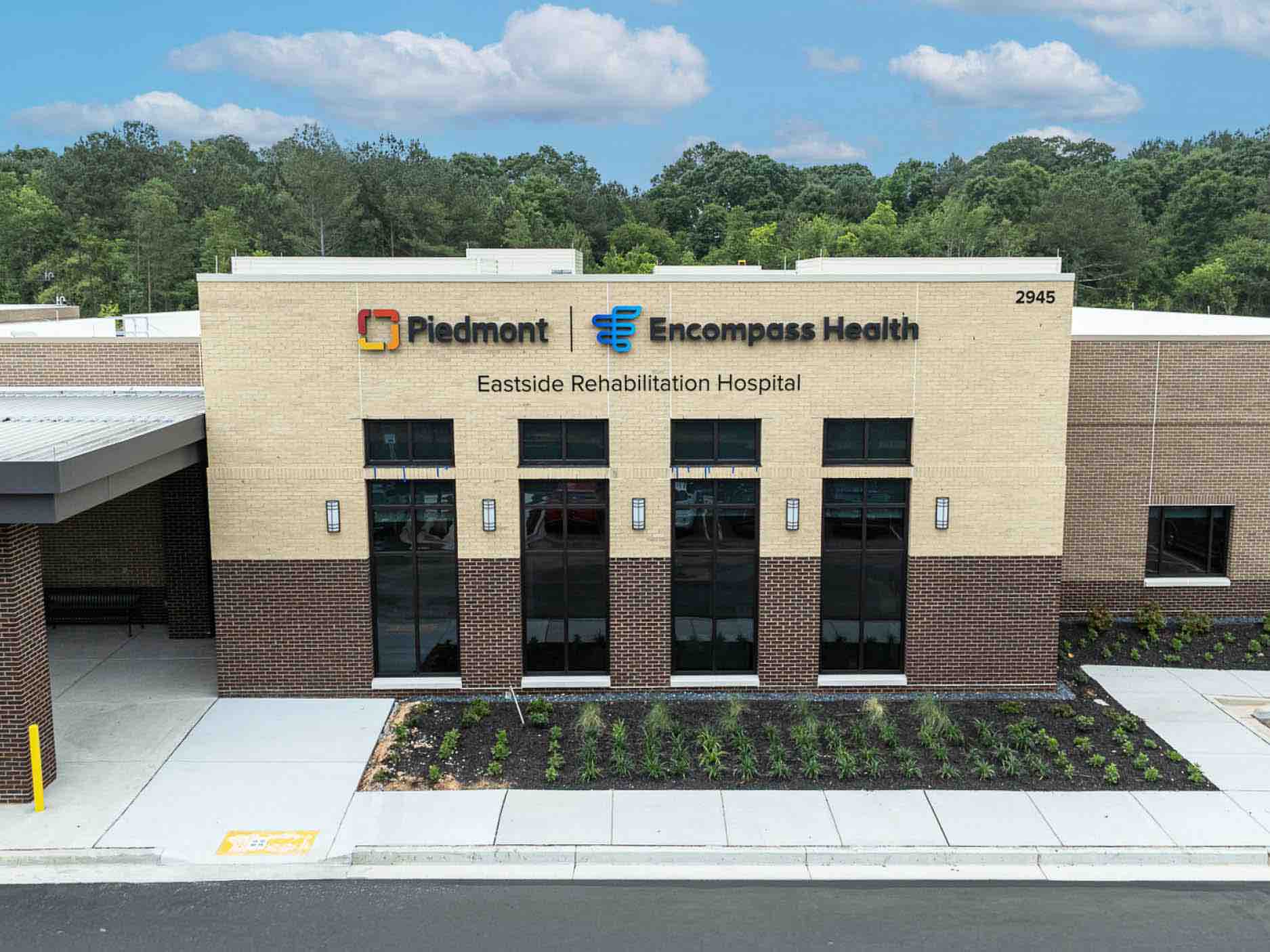 Rehabilitation hospital exterior with Piedmont Healthcare Encompass Health Eastside Rehabilitation Hospital signage, featuring a brick facade, large windows and landscaped entrance