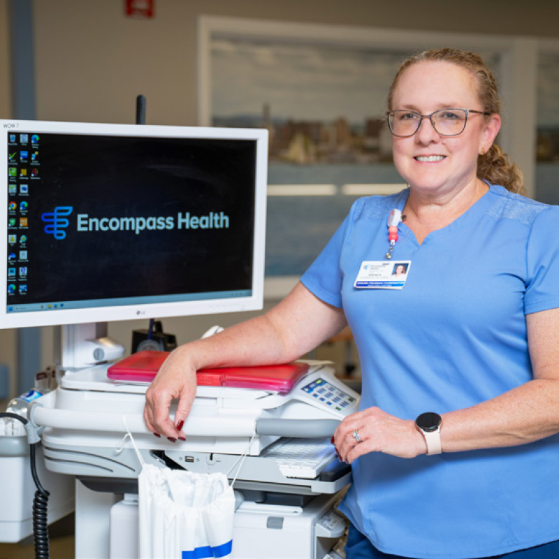 Wound Care Coordinator Brenda Overholts smiles beside a computer displaying 