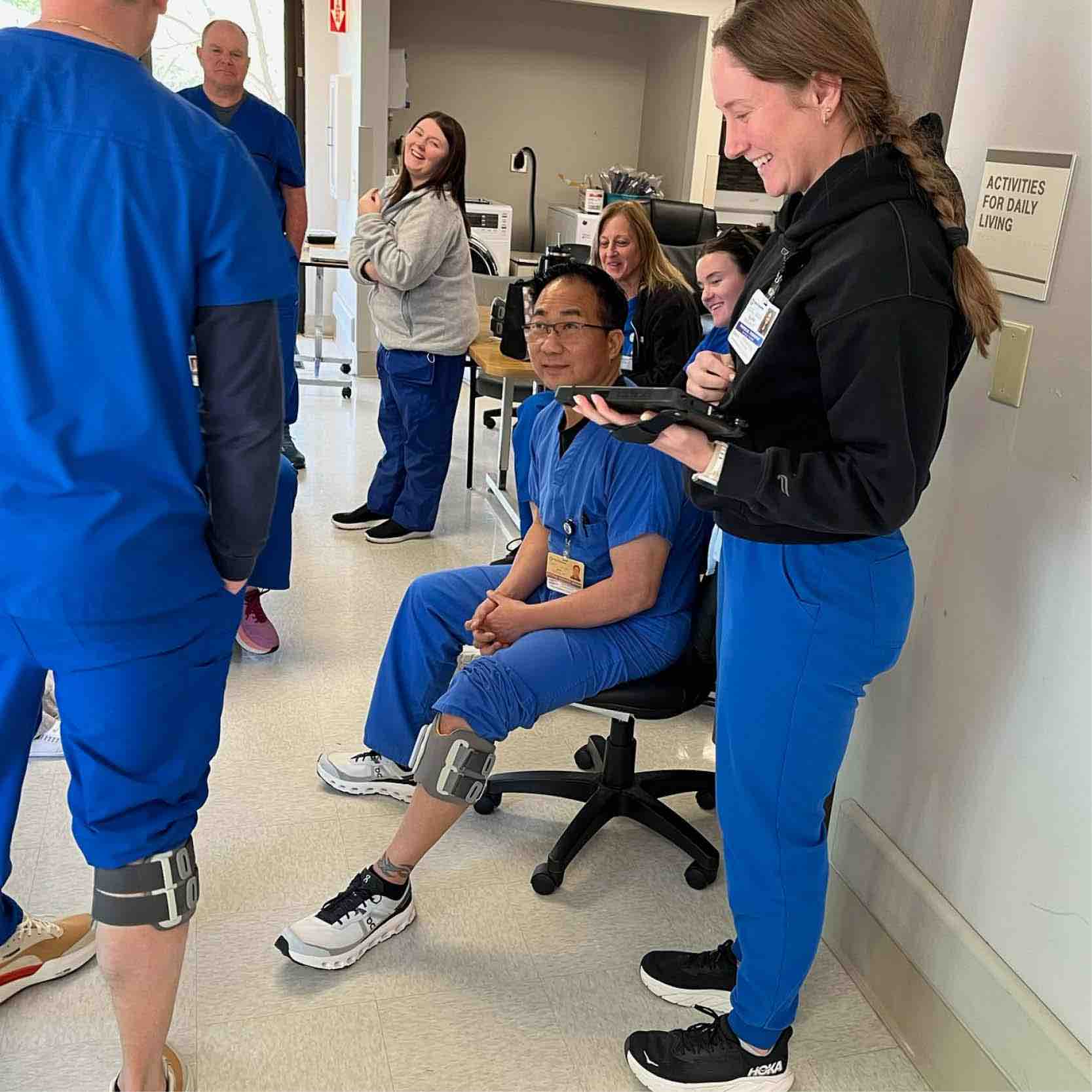Rehabilitation staff observe patient using Bioness L300 device on lower leg during therapy session, demonstrating advanced neurorehabilitation technology to support mobility and gait recovery